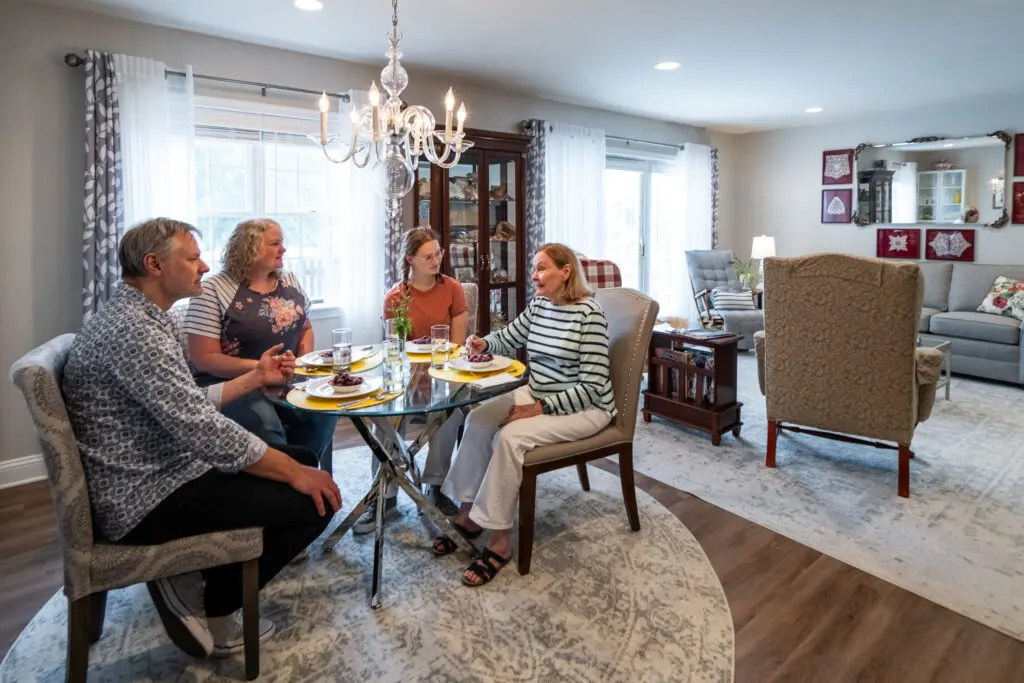 A Residential Living resident and her family enjoy a meal in her home.