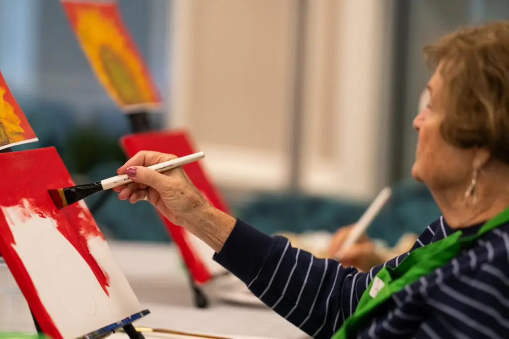 An elderly woman painting in a skilled nursing facility