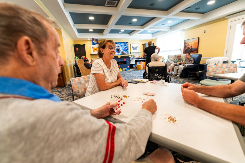 A Health Care resident at Dock Woods enjoys a card game with loved ones