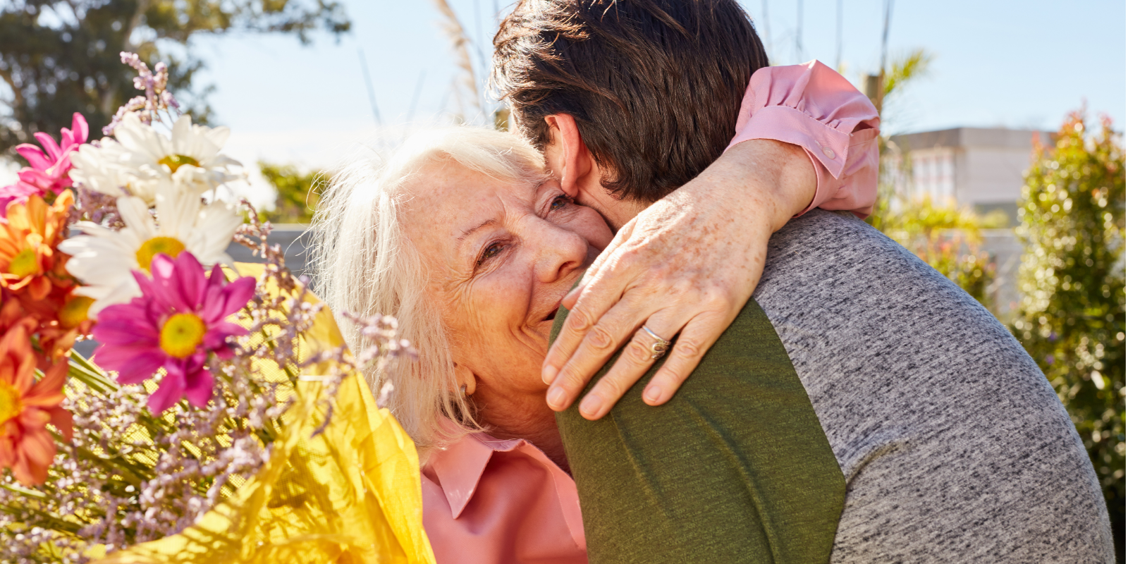 A young man gives a bouquet of flowers to a woman with dementia at a memory care facility