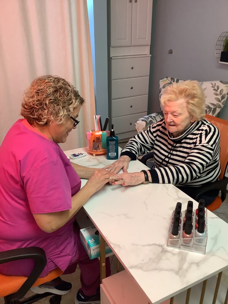 A team member paints the nails of a resident in Memory Care at Dock Woods in Lansdale