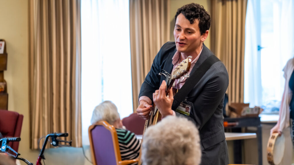 A creative arts therapist plays the guitar with residents at one of Living Branches' Personal Care communities
