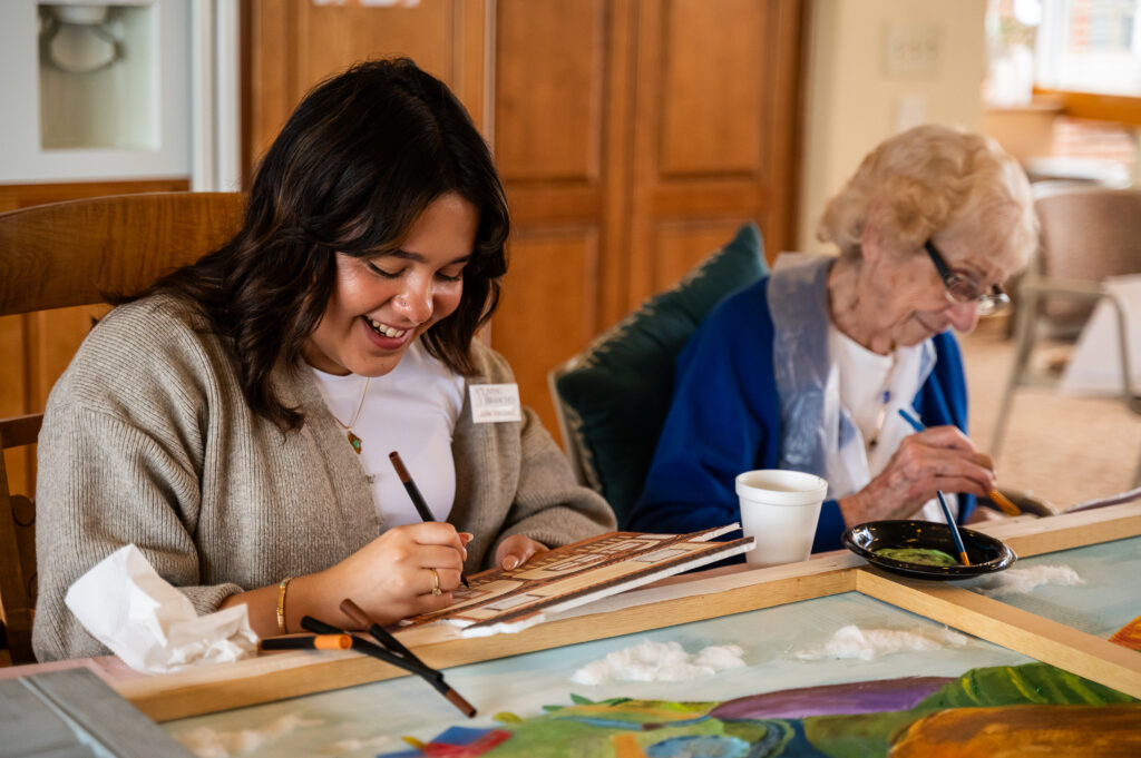 A student works on an art project with a Personal Care resident at The Willows in Hatfield