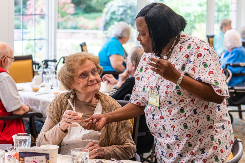 A nurse provides medication to a resident in the dining room at Living Branches' Personal Care community in Lansdale